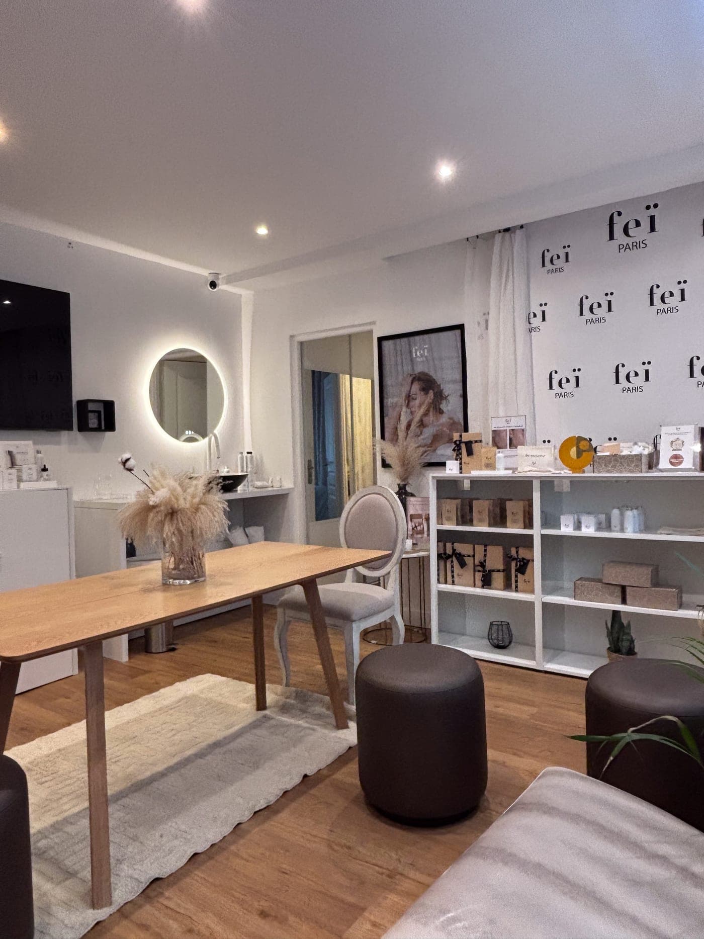 Inside the Feï boutique: a large wooden table, a round backlit mirror and shelves of products